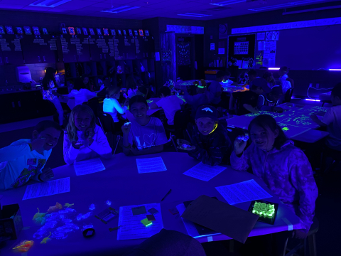 Students studying math concepts in the dark with the help of glow sticks.