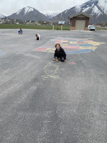 Students drawing shapes on the playground with chalk.