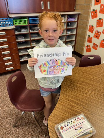 A student showing her picture labeled "Friendship Pie."