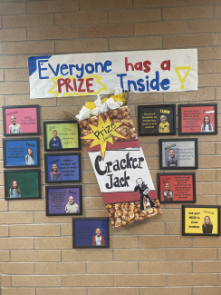 Kindness wall with poster "Everyone has a Prize Inside" and a cracker jack box with student pictures surrounding it.