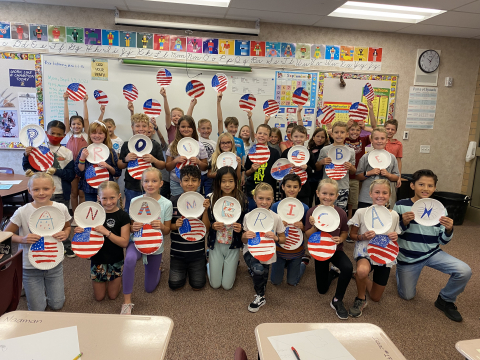 Students hold American flag art project. They are learning about the rights and responsibilities they have as U.S. citizens.
