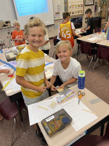 Students enjoying a STEM project using popsicle sticks to build bridges.