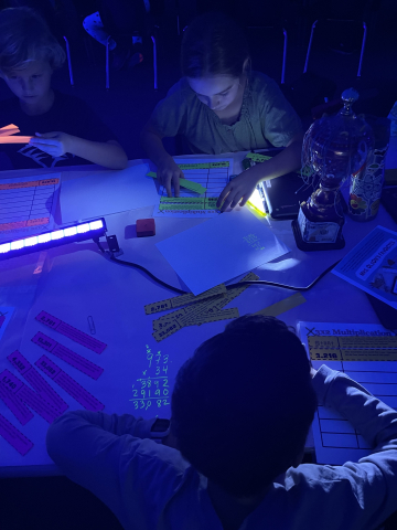 Students working in the dark, using black lights to make their math glow.