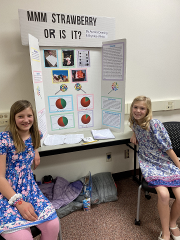 Students in front of science fair project. 