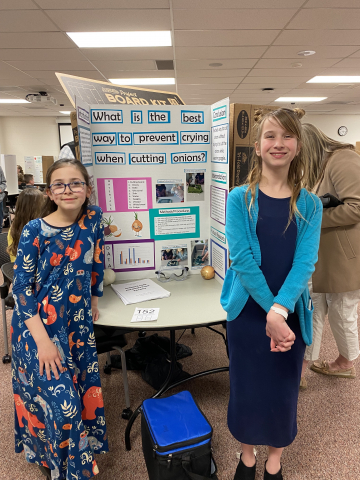 Students in front of science fair project. 