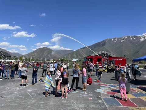 Fire truck shooting water on students at field day.