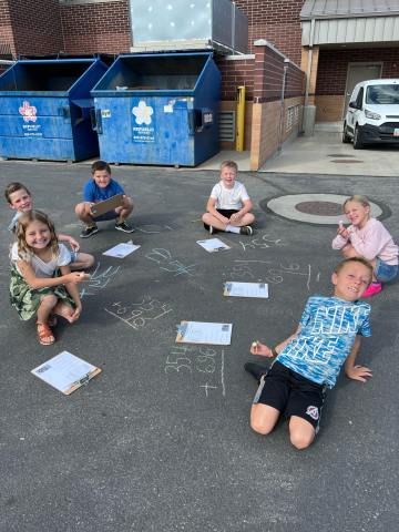 Students doing math outside with chalk.