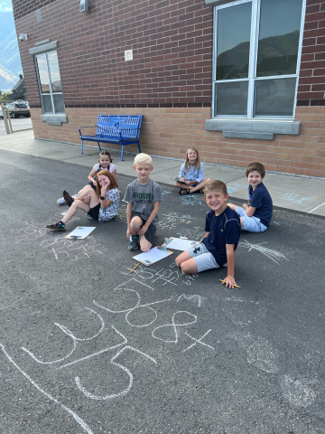 Students doing math outside with chalk.