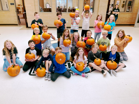 Students holding pumpkins.