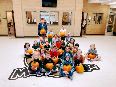 Students holding pumpkins.