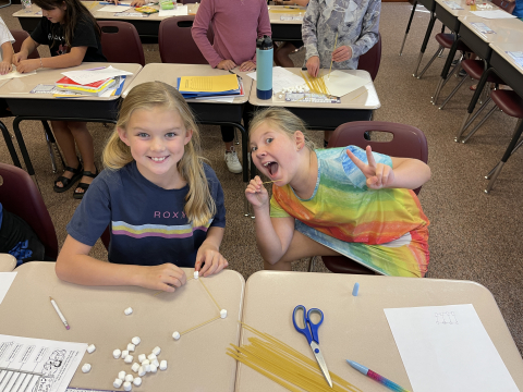Students using spaghetti noodles and marshmallows to build a sturdy structure.