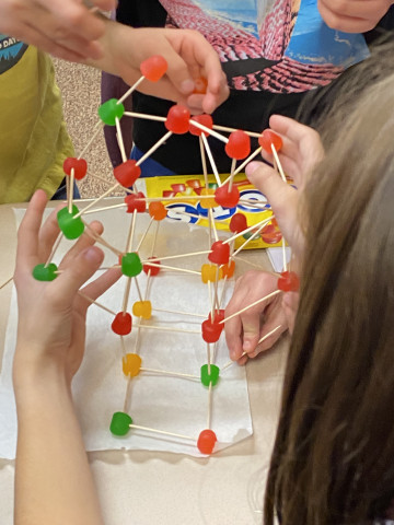Students constructing a Christmas Tree with just toothpicks and Dots candy.