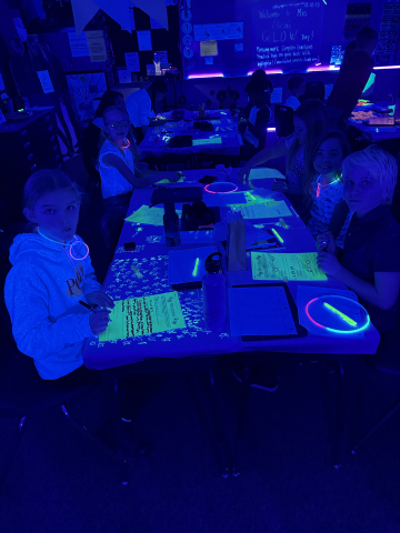 Students working in the dark with various items glowing.