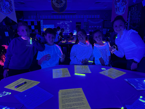 Students working in the dark with various items glowing.