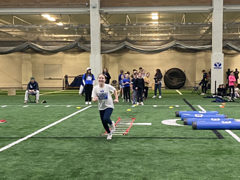 Students running on the indoor practice field.