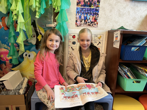 Third grader and kindergartner reading a book together.