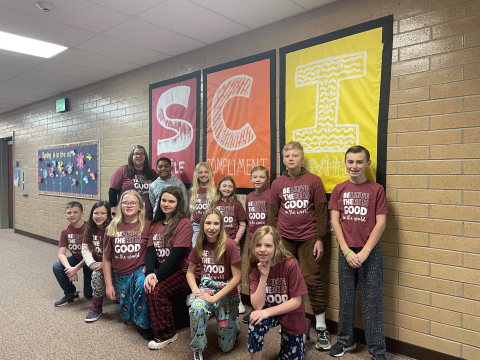 Student Council in front of the sign at school reminding us to smile, compliment, and invite.