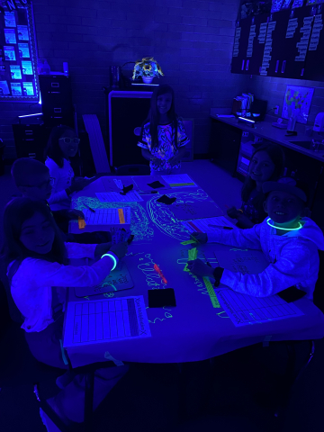 Students studying math concepts in the dark with the help of glow sticks.
