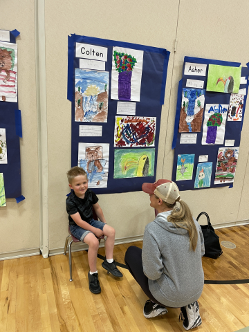 A student talking to a parent about their artwork.