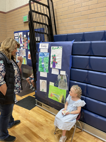 A student talking to a parent about their artwork.