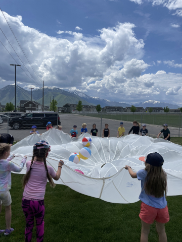 Students outside playing with a parachute.