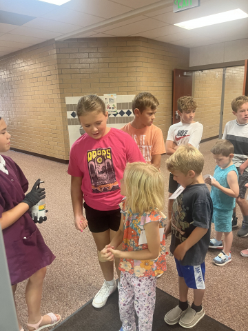 5th grade students helping kindergarten students in the halls during lunch.