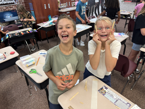 Students working together to make a bridge out of popsicle sticks.