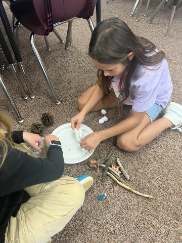 Two students arranging objects in order to tell a story.