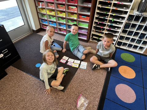 Kids sitting on the floor with cards that have sequence words on them.