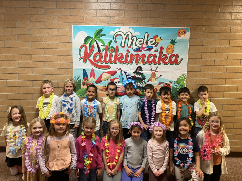 Class picture in front of Mele Kalikimaka sign.