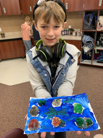 A student showing their play dough model.