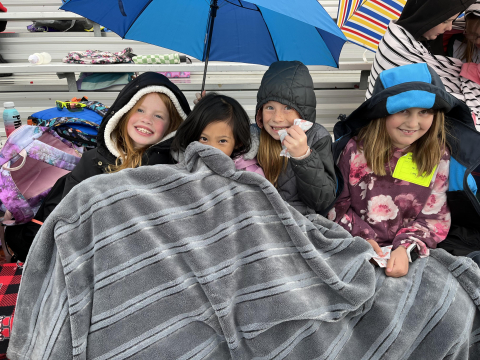 Students huddled under blankets on the bleachers.