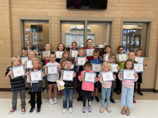 Students holding certificates recognizing them for demonstrating perseverance.
