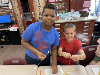 Students using spaghetti noodles and marshmallows to build a sturdy structure.