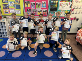First grade students holding up work.