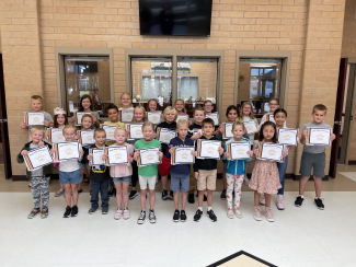Students holding up their certificates for Student of the Month.