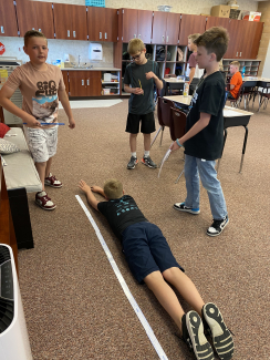 Student laying on the floor to measure the height of the 9-square.