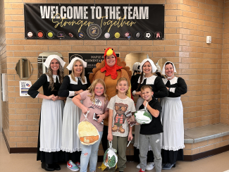 Students holding their turkeys. Office staff dressed as a turkey and pilgrims.