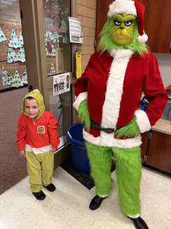 Student standing by the Grinch who visited kindergarten.